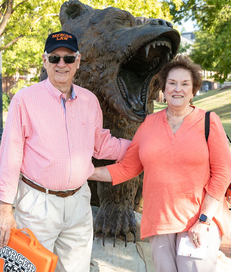 Man and woman standing in front of bear statue